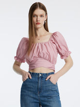 A lady wears a pink crop top.